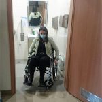 Na zdjęciu kobieta siedząca na wózku inwalidzkim, wyjeżdżająca z toalety dostosowanej do potrzeb osób z niepełnosprawnościami. Kobieta w ramach szkolenia doświadcza niepełnosprawności.