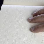 Po kartce z wydrukowanym tekstem w alfabecie Braille'a palcami przesuwa się męska dłoń.