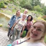 Pamiątkowe zdjęcie w ogrodzie botanicznym: przedstawicielka Uniwersytetu Adama Mickiewicza w Poznaniu wraz z pracownikami UJK w Kielcach w tle bujna flora ogrodu.